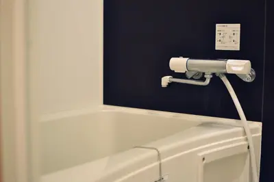 a bathroom with a white bathtub with a hose at TOKYO-W-INN Asakusa in Tokyo