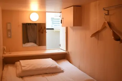 a small room with a bed and a mirror at TOKYO-W-INN Asakusa in Tokyo