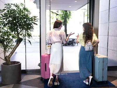 two women standing in a lobby with their luggage at Tokyu Stay Yotsuya - Shinjuku Area in Tokyo
