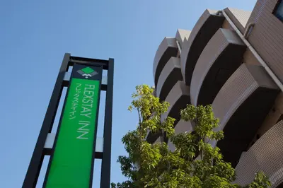 a green sign in front of a building at FLEXSTAY INN Sugamo in Tokyo