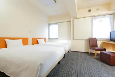 a hotel room with two beds and a tv at FLEXSTAY INN Sugamo in Tokyo