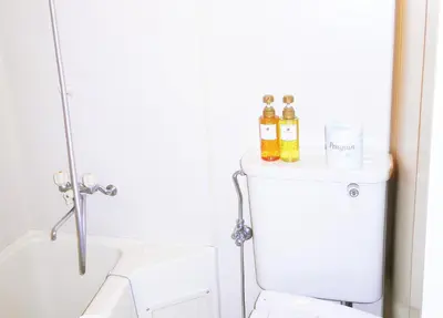 a bathroom with a toilet and two bottles of alcohol at FLEXSTAY INN Sugamo in Tokyo