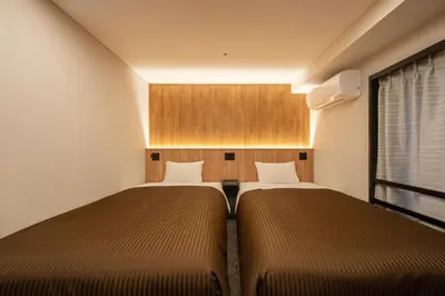 two beds in a small room with a window at Belmont Hotel in Tokyo