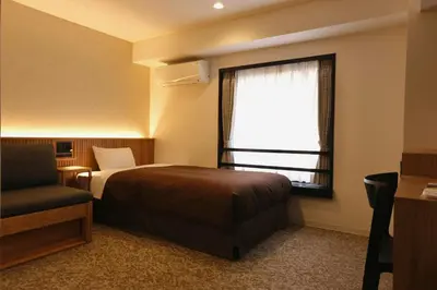 a bedroom with a bed and a window and a chair at Belmont Hotel in Tokyo