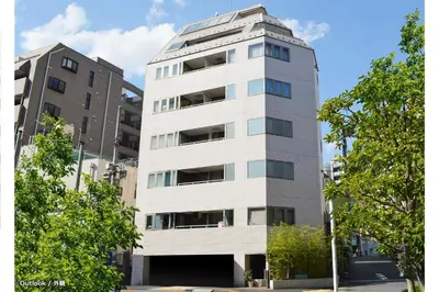 a tall white building with trees in front of it at Tokyo Tower View Guest House in Tokyo