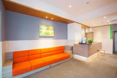 an orange couch in a room with a counter at Tokyu Stay Yoga in Tokyo