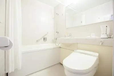 a white bathroom with a toilet and a sink at Tokyu Stay Yoga in Tokyo