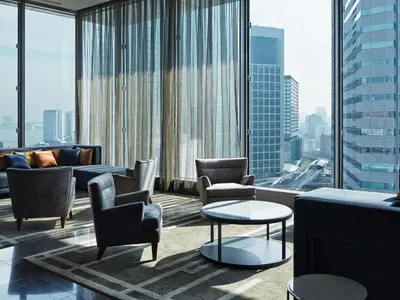 a living room with chairs and tables and large windows at Mitsui Garden Hotel Ginza Premier in Tokyo