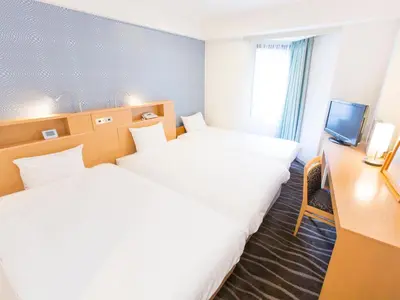 a hotel room with two beds and a desk at Shibuya Tobu Hotel in Tokyo