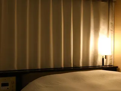 a bedroom with a bed and a lamp next to a window at APA Hotel Iidabashi Ekiminami in Tokyo