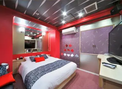 a bedroom with a bed in a room with red walls at Hotel California Kaminarimon (Adult Only) in Tokyo
