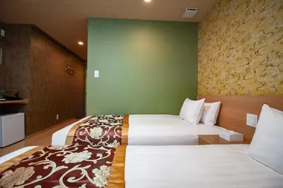 a hotel room with two beds and a green wall at Nagomi Hotel Nippori in Tokyo