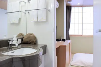 a bathroom with a sink and a bed at Nagomi Hotel Nippori in Tokyo