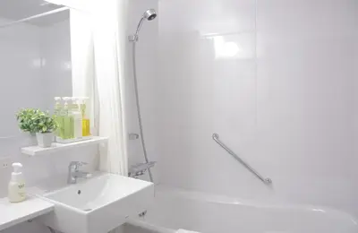 a white bathroom with a shower and a sink at Nagomi Hotel Nippori in Tokyo