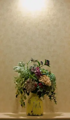 a yellow vase with a bunch of flowers in it at Nagomi Hotel Nippori in Tokyo