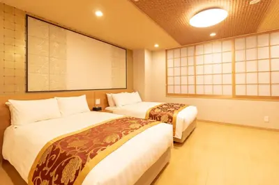 a hotel room with two beds and a large screen at Nagomi Hotel Nippori in Tokyo