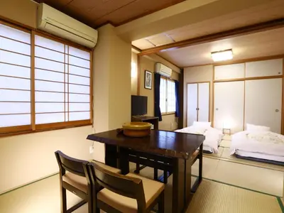 a room with a desk and a bed and a table and chairs at Ryokan Kamogawa Asakusa in Tokyo