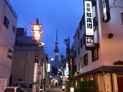 a busy city street with a tv tower in the background at Ryokan Kamogawa Asakusa in Tokyo