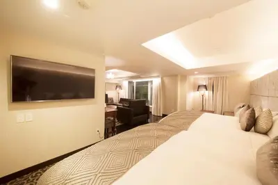 a hotel room with a large bed with a television on the wall at The Centurion Classic Akasaka in Tokyo