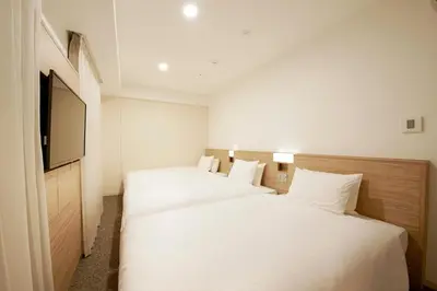 a hotel room with two beds and a television at Sotetsu Fresa Inn Tokyo Kinshicho in Tokyo