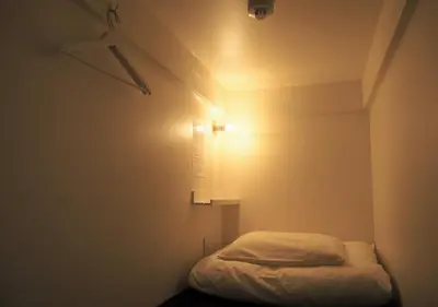 a small bed in a room with a light at almond hostel & cafe Shibuya in Tokyo