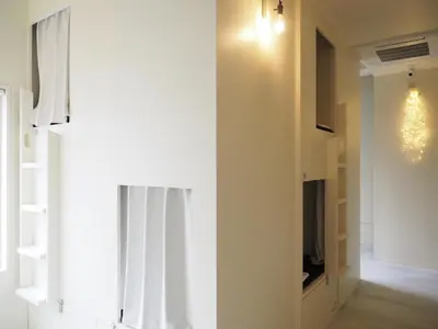 a living room with a white wall and a window at almond hostel & cafe Shibuya in Tokyo