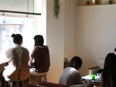 a group of people sitting around a table in a room at almond hostel & cafe Shibuya in Tokyo