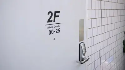 a white tiled bathroom door with a sign on it at almond hostel & cafe Shibuya in Tokyo