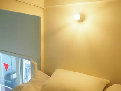 a light on the wall of a room with a bed at almond hostel & cafe Shibuya in Tokyo