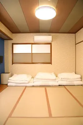 a room with two beds in a room with a light at Tokyo Ueno New Izu Hotel in Tokyo