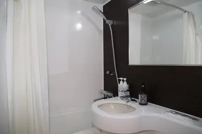 a white bathroom with a sink and a mirror at Tokyo Ueno New Izu Hotel in Tokyo