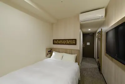 a bedroom with a white bed and a flat screen tv at Hotel Il Fiore Kasai in Tokyo