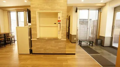 a room with a refrigerator and a table and chairs at House Ikebukuro in Tokyo