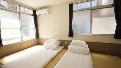 two beds in a room with two windows at House Ikebukuro in Tokyo