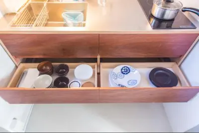 a wooden drawer with dishes and utensils in it at URBAN LODGE Komagome in Tokyo