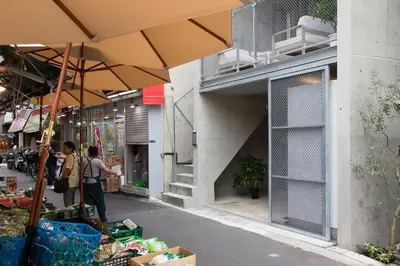 a couple of people standing in a market with umbrellas at URBAN LODGE Komagome in Tokyo