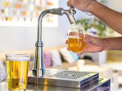 a man holding a glass of beer next to a drink at The Millennials Shibuya in Tokyo