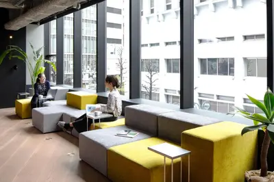 two people sitting in a room with windows at The Millennials Shibuya in Tokyo
