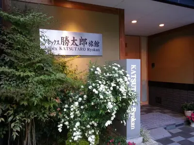 a sign on the side of a building with white flowers at Annex Katsutaro Ryokan in Tokyo