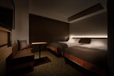 a hotel room with two beds and a couch at Nest Hotel Tokyo Hanzomon in Tokyo