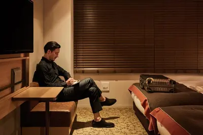 a man sitting on a chair in a hotel room at Nest Hotel Tokyo Hanzomon in Tokyo