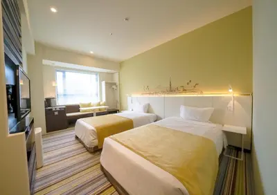 a hotel room with two beds and a couch at Ours Inn Hankyu in Tokyo