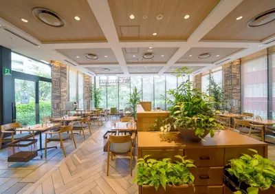 a restaurant with tables and chairs and plants at Ours Inn Hankyu in Tokyo