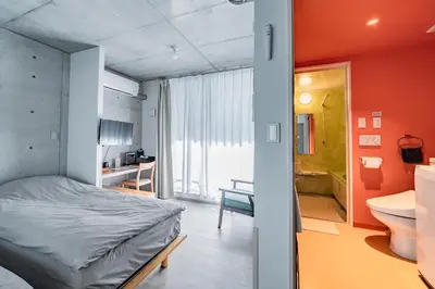 a bedroom with a bed and a bathroom with a sink at bmj Shinjuku Okubo in Tokyo