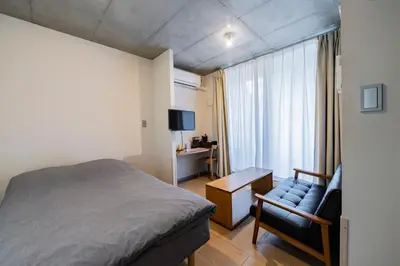 a bedroom with a bed and a chair and a desk at bmj Shinjuku Okubo in Tokyo