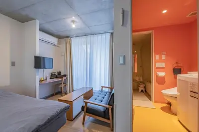a bedroom with a bed and a desk and a bathroom at bmj Shinjuku Okubo in Tokyo
