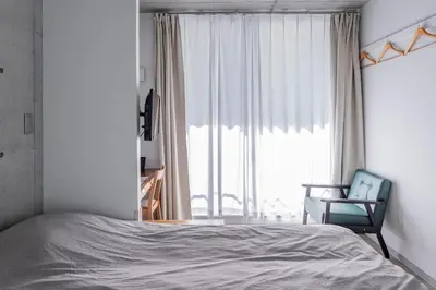a bedroom with a bed and a chair and a window at bmj Shinjuku Okubo in Tokyo