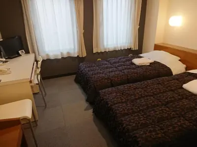 a hotel room with two beds and a desk at Residence Hotel Will Shinjuku in Tokyo