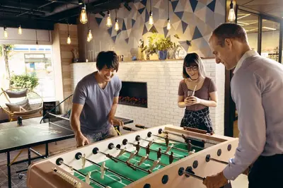 a group of three people playing a game of foosball at MOXY Tokyo Kinshicho in Tokyo