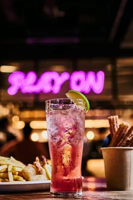 a drink with a lime on a table with a plate of food at MOXY Tokyo Kinshicho in Tokyo